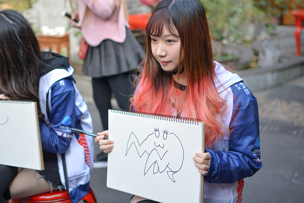 游戏规则如下:第一名队员抽签选择英雄联盟中的英雄,模仿裁判提供的